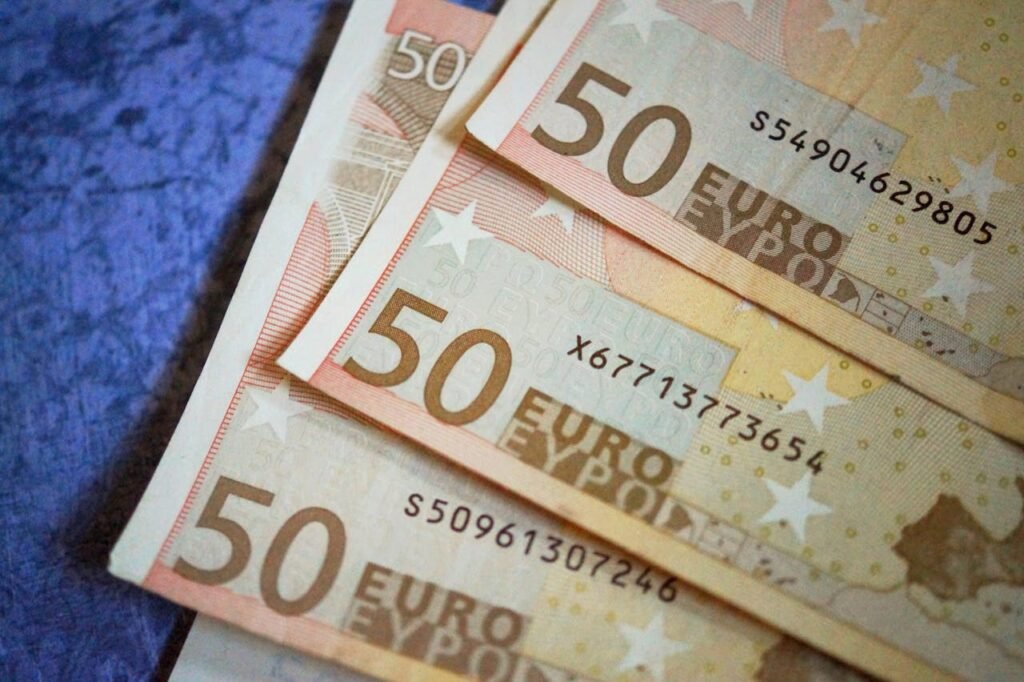 Stack of 50 Euro notes arranged on a textured surface, emphasizing European currency.