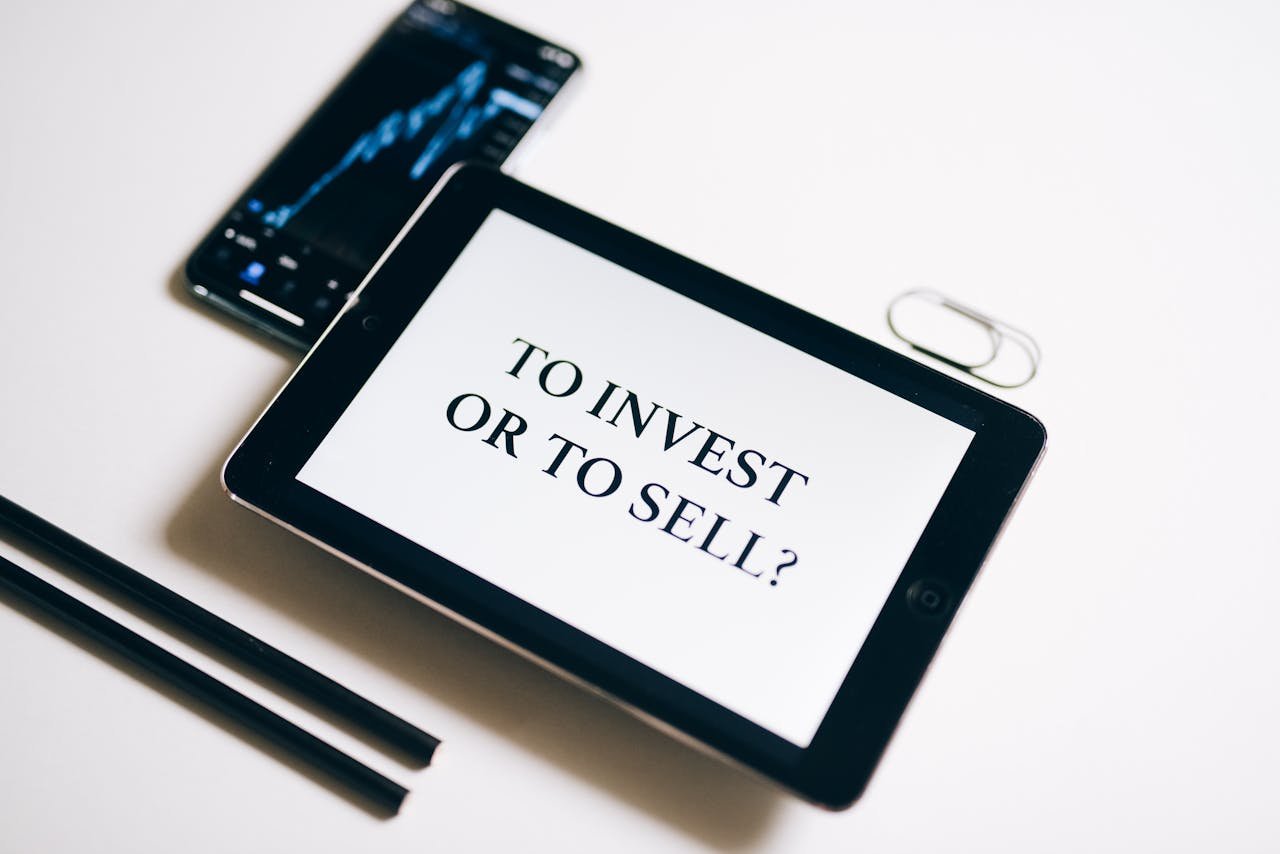 A tablet with text 'To Invest or To Sell?' on a white background.